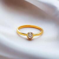 Elegant golden ring with a brilliant diamond resting on soft silky fabric in natural light photo