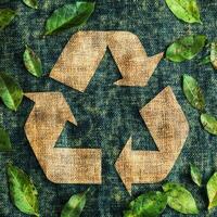 Symbol of sustainability with natural leaves surrounding a recycling emblem on a textured fabric background photo