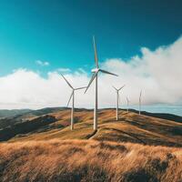 Wind turbines stand tall on rolling hills under a clear blue sky in a remote area of nature during daylight hours photo