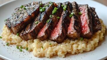Juicy steak, grilled to perfection, served on smooth mashed potatoes and garnished with herbs photo