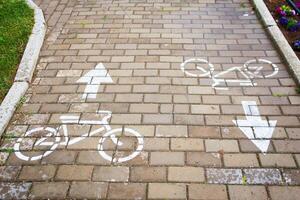 A brick walkway adorned with bicycles and arrows painted on the surface, creating a charming and unique path for pedestrians to enjoy photo