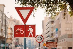 A red traffic sign in the neighbourhood features a bicycle and pedestrian symbol, promoting safety and shared use of the road infrastructure during daytime photo