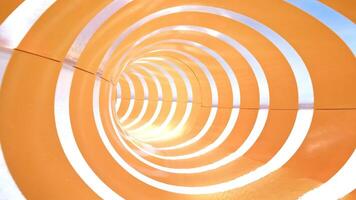 Water flows into a vibrant orange and white waterslide, creating a lively scene at an amusement park on a sunny day video