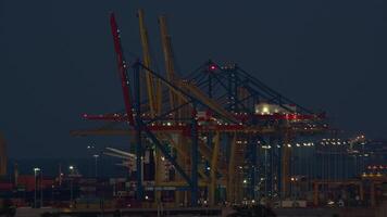 Container ship unloading occurs at night in a large industrial port, showcasing cranes in action and bustling logistics video