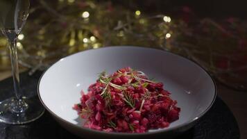 Festive beetroot salad featuring greens and garnished with dill, accompanied by a glass of sparkling wine on a holiday table video