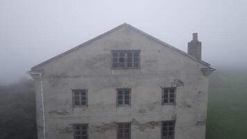 Fog envelops an abandoned house, creating an atmosphere of mystery and eeriness in a rural setting video