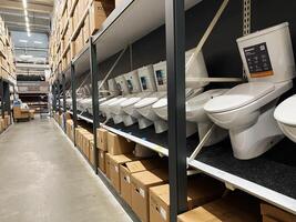 Kyiv, Ukraine - January 03, 2025 Row of toilet displays in a warehouse store with stacked boxes photo
