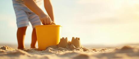 Building sandcastle with yellow bucket on beach at sunset photo