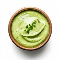 Creamy avocado dressing in wooden bowl, garnished with herbs, top view photo