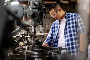 In a factory, a worker operates a lathe grinder to achieve a smooth finish on steel. photo