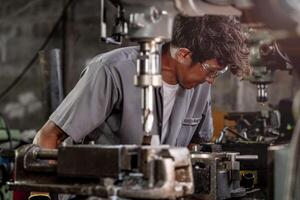 In a factory setting, a professional worker operates a drilling machine for accurate metalwork. photo