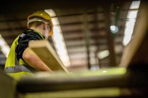 A man and his team clean, inspect, and prepare wooden items in an industrial warehouse. photo