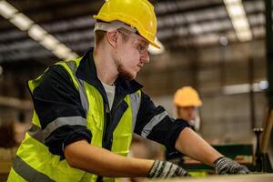 A worker team focuses on cleaning and inspecting timber wood in a dark industrial setting. photo