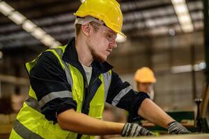 A carpenter cleans and checks wooden items for defects in a production facility. photo