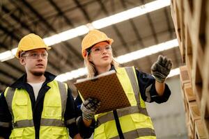 A team of engineers examines timber materials while walking through the warehouse. photo