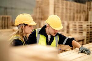 Workers walk through a warehouse, inspecting timber materials for use in manufacturing. photo