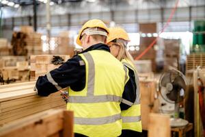 Workers check timber materials in a warehouse environment for production readiness. photo