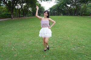 A joyful yo ung woman dances in harmony indoors, with large windows and a scenic view enhancing the freedom and energy. photo