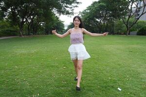 A joyful young woman dances in harmony indoors, with large win dows and a scenic view enhancing the harmony and peace. photo