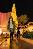 a little girl in a green coat standing in front of a christmas tree photo