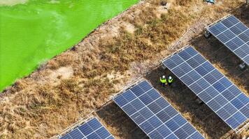 Aerial view of technician s working under solar panels in a dry field, emphasizing renewable energy innovation, sustainable development, and environmental responsibility in a rural setting. photo