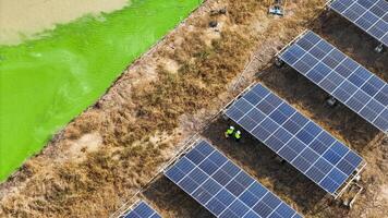Aerial view of technicians working un der solar panels in a dry field, emphasizing renewable energy innovation, sustainable development, and environmental responsibility in a rural setting. photo