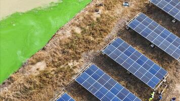 Renewable en ergy setup with solar panels and workers near a vivid waterbody, emphasizing clean energy, eco-friendly practices, and the integration of technology into diverse landscapes. photo