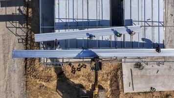 Aerial view of work ers placing long metal sheets onto a building framework with the aid of heavy machinery, highlighting precision, teamwork, and modern techniques in construction projects. photo