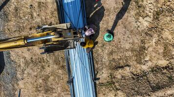Aerial view of workers pla cing long metal sheets onto a building framework with the aid of heavy machinery, highlighting precision, teamwork, and modern techniques in construction projects. photo
