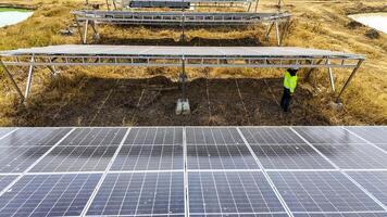 Two workers in safety gear performing maintenance under solar pa nels in a field, highlighting renewable energy, sustainability, and the efficient management of solar power systems in natural settings photo