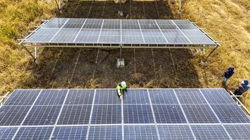 Two workers in safety gear performing maintenance under solar panels in a field, h ighlighting renewable energy, sustainability, and the efficient management of solar power systems in natural settings photo