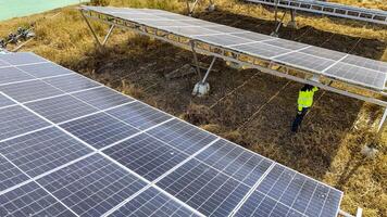 Two workers in safety gear performing maintenance under solar panels in a fiel d, highlighting renewable energy, sustainability, and the efficient management of solar power systems in natural settings photo