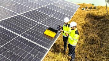 Two workers in safety gear inspecting solar pan els in a field, emphasizing renewable energy, sustainability, and routine maintenance to ensure efficient performance of solar power systems. photo