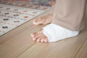 An injured foot wrapped in a bandage is gently resting on the floor, awaiting care and healing photo
