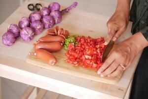 Skillfully Chopping Fresh Vegetables and Sausages in the Kitchen Area photo