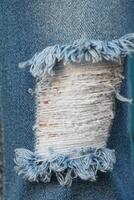 blue jean texture with a hole and ripped threads showing photo