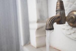 An Elegant Brass Faucet with Beautiful Flowing Water in a Marble Setting photo