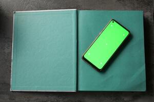 A Green Phone resting on an Open Book An Excellent Mockup for Digital Content photo