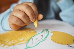 A child is happily coloring a lemon illustration using a vibrant crayon photo