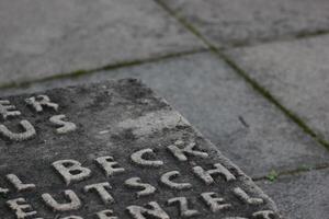 Detail of memorial for resistance fighters against National Socialism in WWII. Unidentifiable fragments of names can be seen on the stone panel. photo