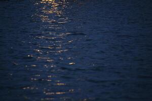 Reflections of yellow light on water in the night. photo