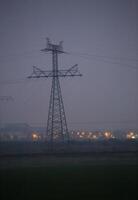 Landscape with power lines in dusk in Mecklenburg-Vorpommern, Germany. The city in the background is Greifswald. photo