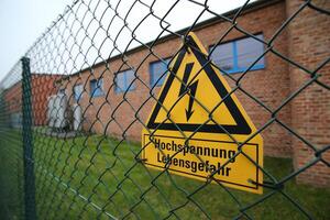 High voltage sign on a fence in Germany. The lower lines mean high voltage life danger. photo