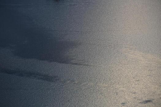 Water surface frozen to a rippled structure, sunlight reflections on the right. photo