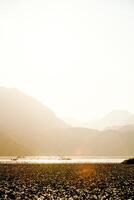 Landscape of blue deep lake in light of sun in daytime, clouds in sky, mountains flow photo