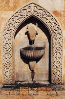 Stone drinking fountain in form of bull head in old part of city photo