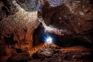 Speleologist explores an underground cave, journey geologist studies hole rock mountain photo