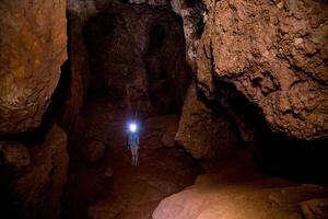 Speleologist explores an underground cave journey, geologist studies hole rock mountain photo