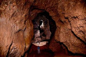 Speleologist explores an underground journey cave, geologist studies hole rock mountain photo