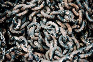 Large big rusty metal chain from ship anchor lying in wooden box, rebar texture photo